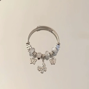 Detailed macro of silver double-wrap charm bracelet with blue beads and crystal butterflies