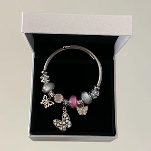 Close-up of beaded stainless steel bracelet with butterfly charms and LOVE engraving