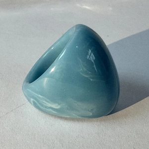 Detail of light blue acrylic ring with marble texture and polished resin finish