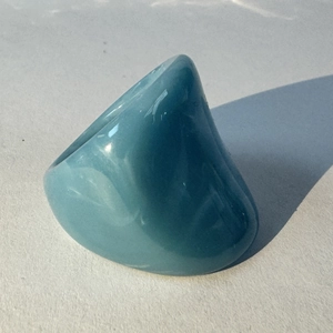 Macro detail of glossy blue acrylic ring with irregular organic oval design