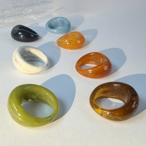 Macro shot of colorful thick acrylic geometric rings in marble, amber, and olive tones
