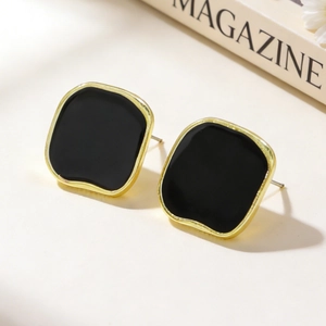 Detailed shot of vintage gold earrings with black enamel in a stylish lifestyle setting