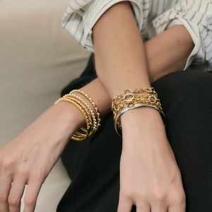 Primer plano de pulseras minimalistas de oro y plata en la muñeca de una modelo