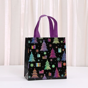 Detail of black non-woven Christmas gift bag with laser patterns and purple handles