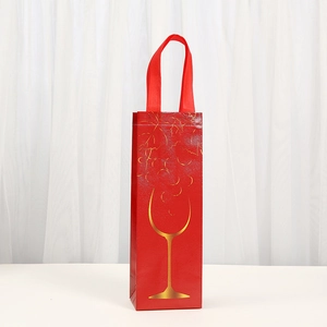 Detail view of red non-woven wine gift bag with gold wine glass and grape pattern