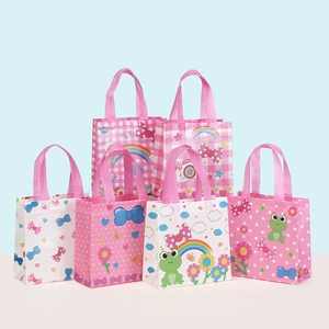 Close-up of assorted pink non-woven gift bags with cute cartoon patterns and ribbon handles
