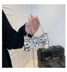 Close-up of a silver metallic bow-shaped mini bag with a sleek mirror finish and chain