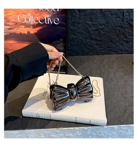 Detailed view of coffee-colored metallic bow mini bag with gold chain strap