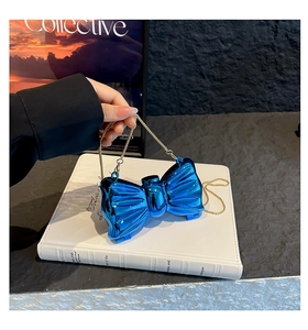 Detail of blue bow-shaped metallic handbag with polished finish and gold chain strap