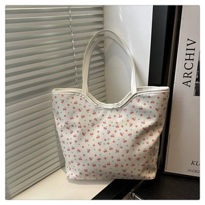 Close-up of white tote bag with red cherry print and sturdy handles in a minimalist interior
