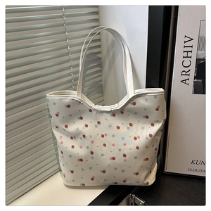 Detail of white tote bag featuring red strawberry and blue flower print on canvas