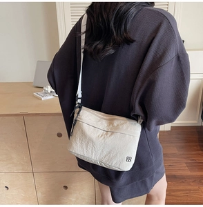 Detail of white nylon crossbody bag with clover logo and unique wrinkled texture
