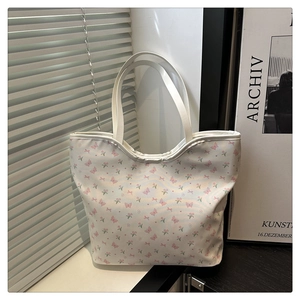 Detail of white tote bag featuring pink butterfly floral prints and curved top handles