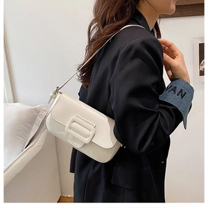 Detailed close-up of a white baguette bag with a large metallic buckle and PU leather texture