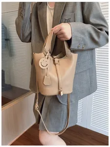 Detail of camel bucket bag in lychee pattern leather with a smiley face charm and metal lock