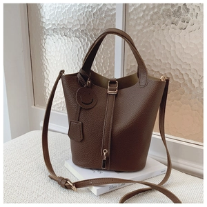 Detail of dark brown pebble leather bucket bag with lock closure and top handle