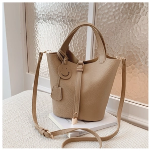 Detail of khaki bucket bag with lychee pattern, gold lock and leather charms on book