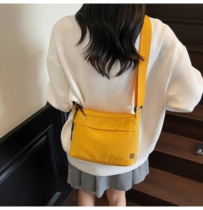 Vista trasera de bolso bandolera de nailon amarillo brillante con cremalleras y asa