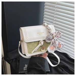 Close-up of luxury white and green plaid handbag with silk scarf handle and gold details