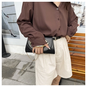 Detailed view of an elegant black leather clutch bag with a golden circular handle