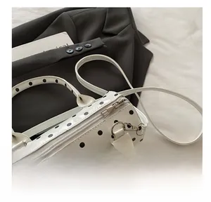 Detailed view of a white polka dot cylindrical bag with smooth metal zipper closure