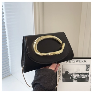 Close-up of minimalist black leather clutch with oversized gold buckle and chain strap