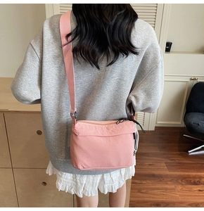 Detalle de bolso bandolera rosa con correa ajustable ancha llevado por una modelo