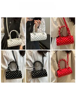 Modèle portant le sac polochon à pois en plusieurs couleurs en bandoulière ou à la main