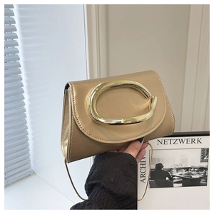 Close-up of champagne gold small square bag with large oval metal handle and chain