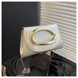 Close-up of elegant silver evening clutch bag featuring a bold gold circular metal buckle