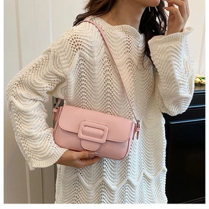 Detailed close-up of a pink matte leather shoulder bag with tonal square buckle detail