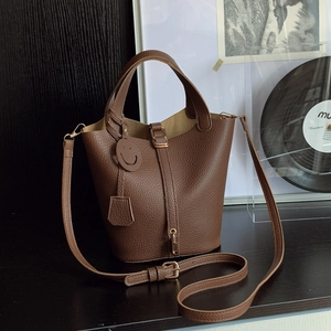 Brown lychee leather bucket bag with top handles and adjustable shoulder strap
