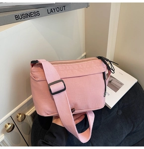 Detalle del bolso bandolera de nailon rosa con cierre de cremallera y correa ajustable
