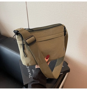 Detalle de bolso bandolera de nailon verde oliva con correa ancha y bolsillo con cremallera
