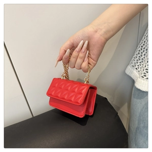 Detail of a red mini quilted handbag with gold chain handle and elegant stitching