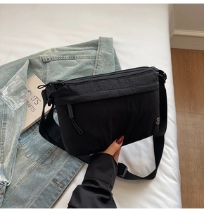Detalle del bolso bandolera de nailon negro con cremalleras multicapa y correa ancha de tela
