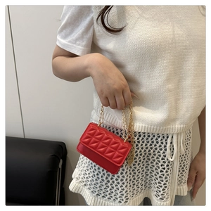 Close-up of red quilted mini crossbody bag with gold chain strap on model