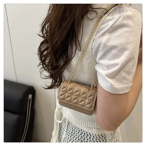 Detail of beige quilted mini crossbody bag with golden chain strap on a model's shoulder