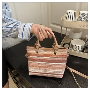 Close-up of woven bucket bag featuring pink gradient stripes and knotted handle details