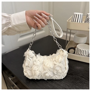 Macro shot of white 3D floral petals on luxury handbag with silver chain strap