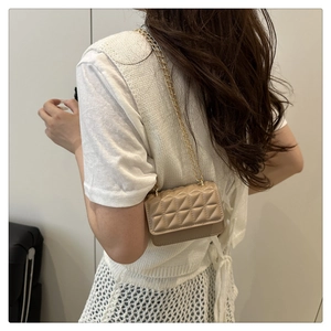 Close-up of beige quilted mini chain bag worn by a model in a minimalist style