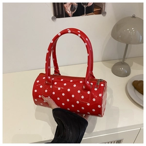 Detailed view of red polka dot barrel bag with glossy finish and silver metal zipper