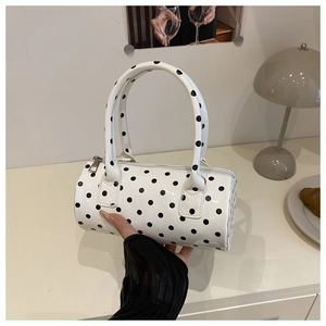 Detailed macro of white cylinder handbag with black polka dots and silver zipper finish