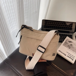 Bolso bandolera minimalista de nailon beige con correa ajustable y logo de trébol metálico