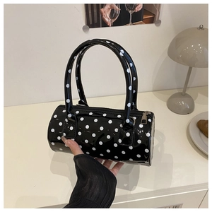 Detailed view of the mini polka dot cylinder handbag in shiny black patent leather finish