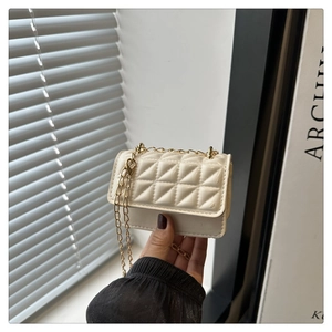 Close-up of creamy white quilted mini bag with gold chain strap held by hand