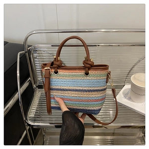 Close-up of colorful striped woven bucket bag with brown leather strap and gold hardware