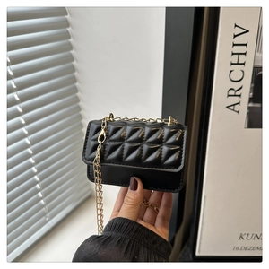 Detail of black quilted PU leather crossbody bag with elegant gold chain strap