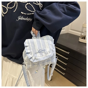 Close-up of blue plaid mini backpack featuring ruffled flap and fashion embroidery detail