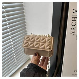 Detail shot of a hand holding the khaki quilted mini bag with golden chain strap